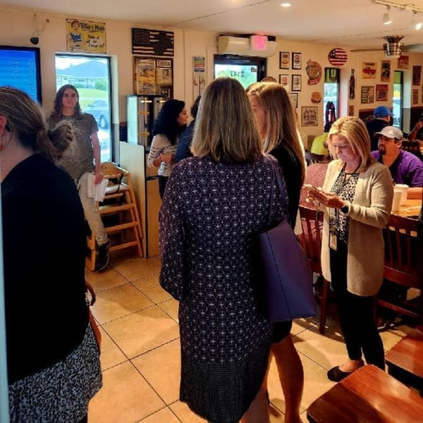 Customers standing and sitting inside Paige's Root Beer, an American restaurant with vintage decor.