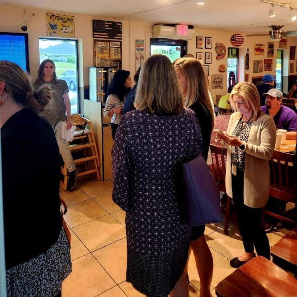 Customers standing and sitting inside Paige's Root Beer, an American restaurant with vintage decor.